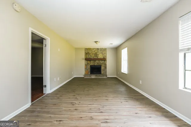 a view of an empty room with wooden floor and closet