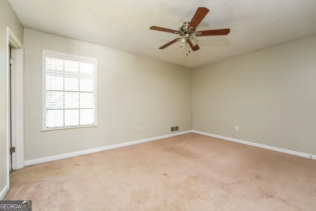 an empty room with a ceiling fan and a window