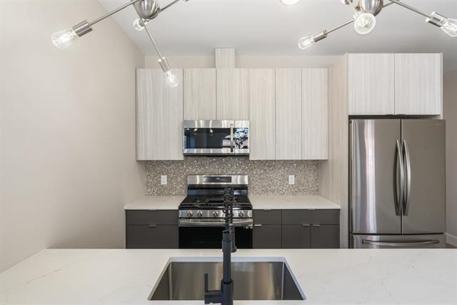 6110 Fillmore Place, Unit 1 West New York, NJ 07093 - Photo 2 of 7 a kitchen with kitchen island a counter space a stove and a refrigerator