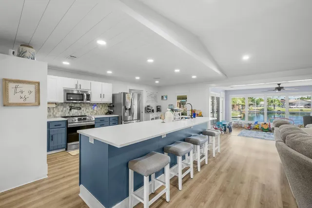 a large white kitchen with a large window and stainless steel appliances