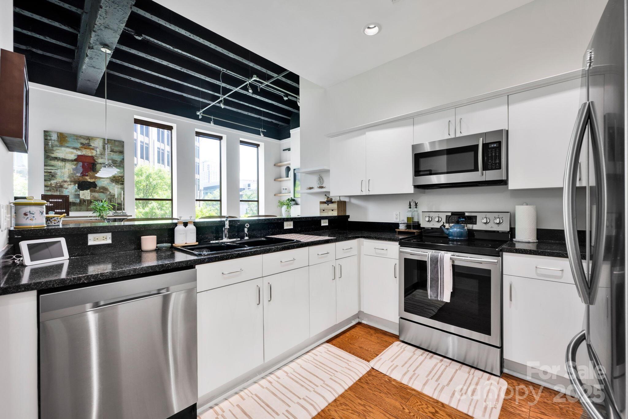 127 North Tryon Street, Unit 404 Charlotte, NC 28246 - Photo 14 of 22 a kitchen with stainless steel appliances granite countertop a stove a sink and a microwave