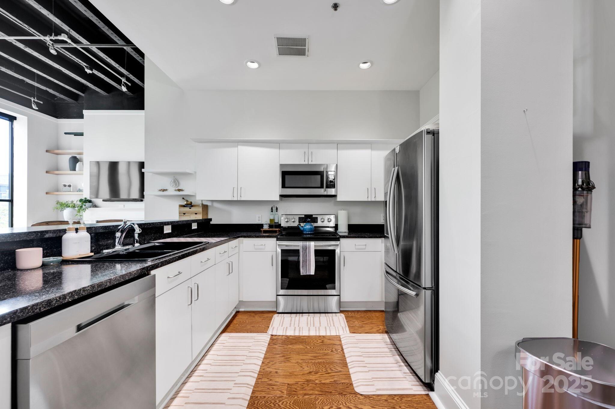 127 North Tryon Street, Unit 404 Charlotte, NC 28246 - Photo 15 of 22 a large kitchen with stainless steel appliances kitchen island granite countertop a refrigerator and a stove top oven