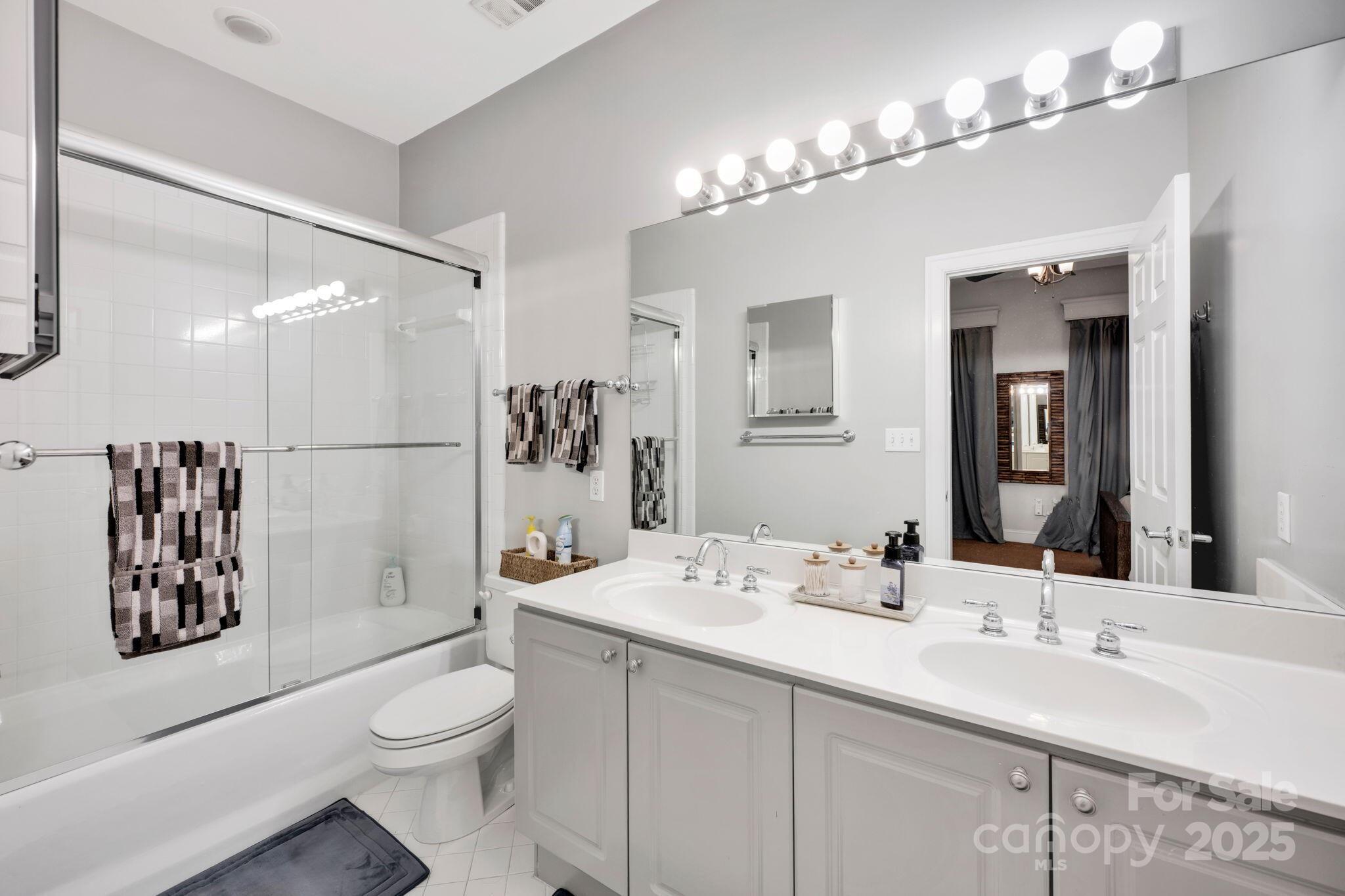 127 North Tryon Street, Unit 404 Charlotte, NC 28246 - Photo 8 of 22 a bathroom with a sink a toilet a shower a mirror and vanity