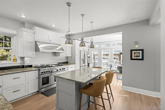 a kitchen with stainless steel appliances a stove a sink dishwasher a refrigerator and a dining table with wooden floor