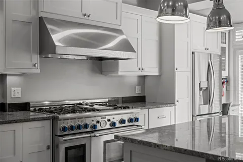 a kitchen with stainless steel appliances granite countertop a stove a refrigerator and a white cabinets