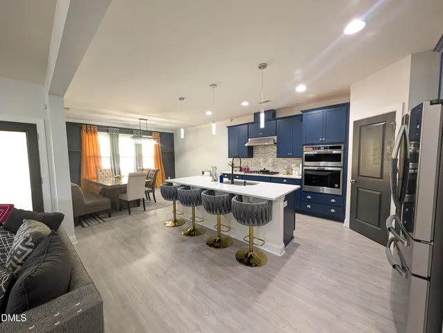 a living room with stainless steel appliances furniture and a kitchen view