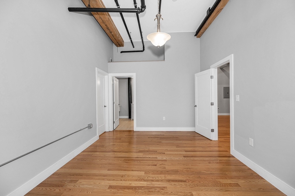 491 Dutton Street, Unit 320 Lowell, MA 01854 - Photo 16 of 31 a view of an empty room with wooden floor and stairs