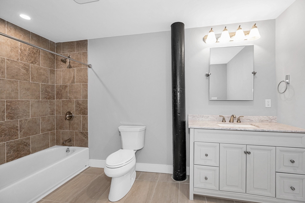 491 Dutton Street, Unit 320 Lowell, MA 01854 - Photo 18 of 31 a bathroom with a toilet a sink a mirror a bathtub and vanity
