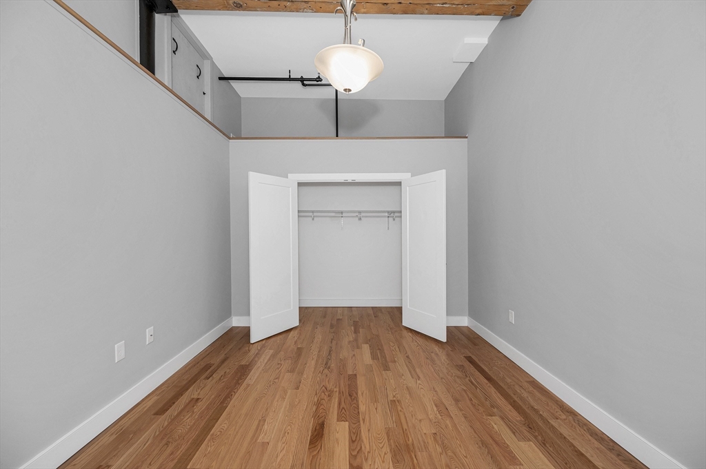491 Dutton Street, Unit 320 Lowell, MA 01854 - Photo 24 of 31 a view of a hallway with wooden floor and chandelier