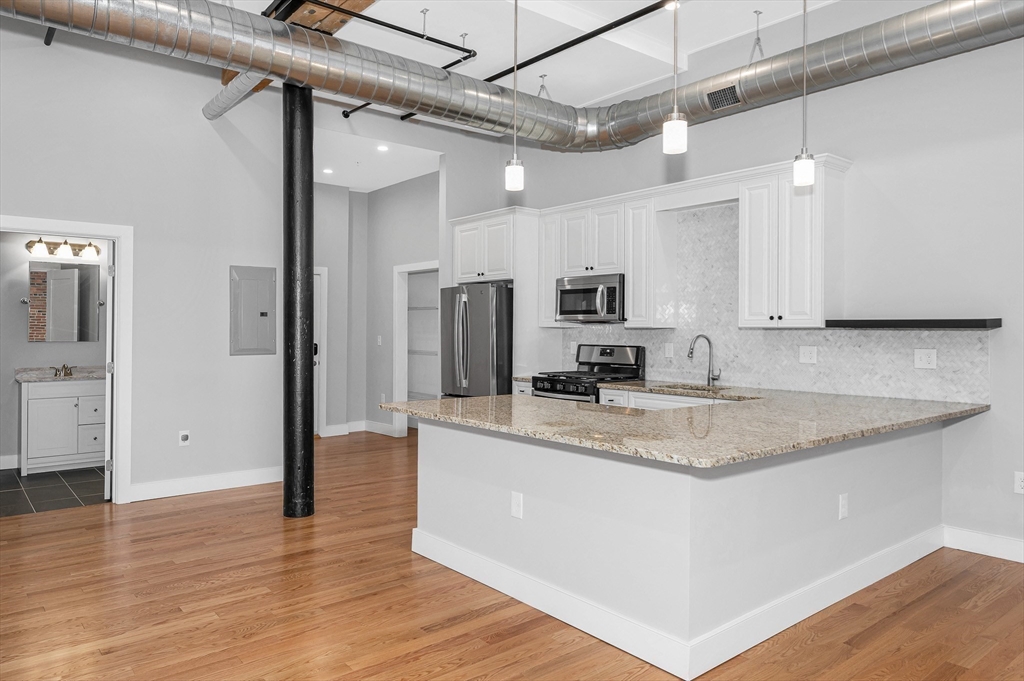 491 Dutton Street, Unit 320 Lowell, MA 01854 - Photo 5 of 31 a view of a kitchen with a sink stainless steel appliances and cabinets