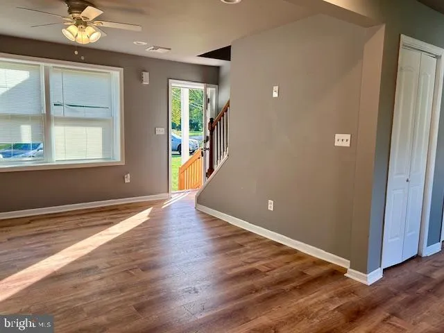 an empty room with wooden floor and windows