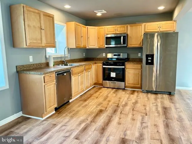 a kitchen with stainless steel appliances granite countertop a stove a sink and a refrigerator