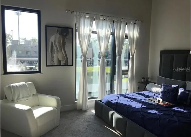 a spacious bedroom with a bed and glass window