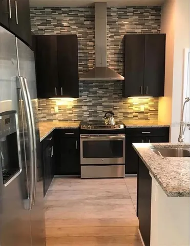 a kitchen with stainless steel appliances granite countertop a stove a sink and a refrigerator