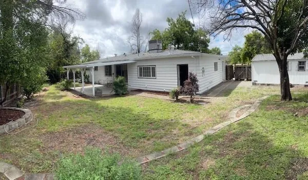 a view of a house with backyard and a tree