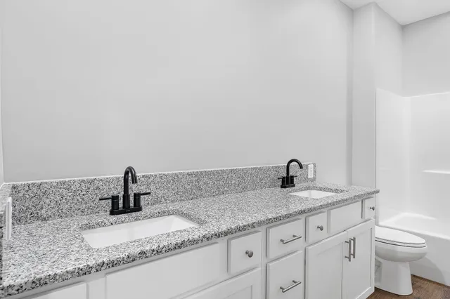 a bathroom with a granite countertop sink and a toilet