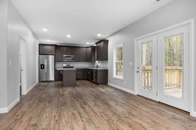 a large kitchen with stainless steel appliances kitchen island a large counter top and wooden floors