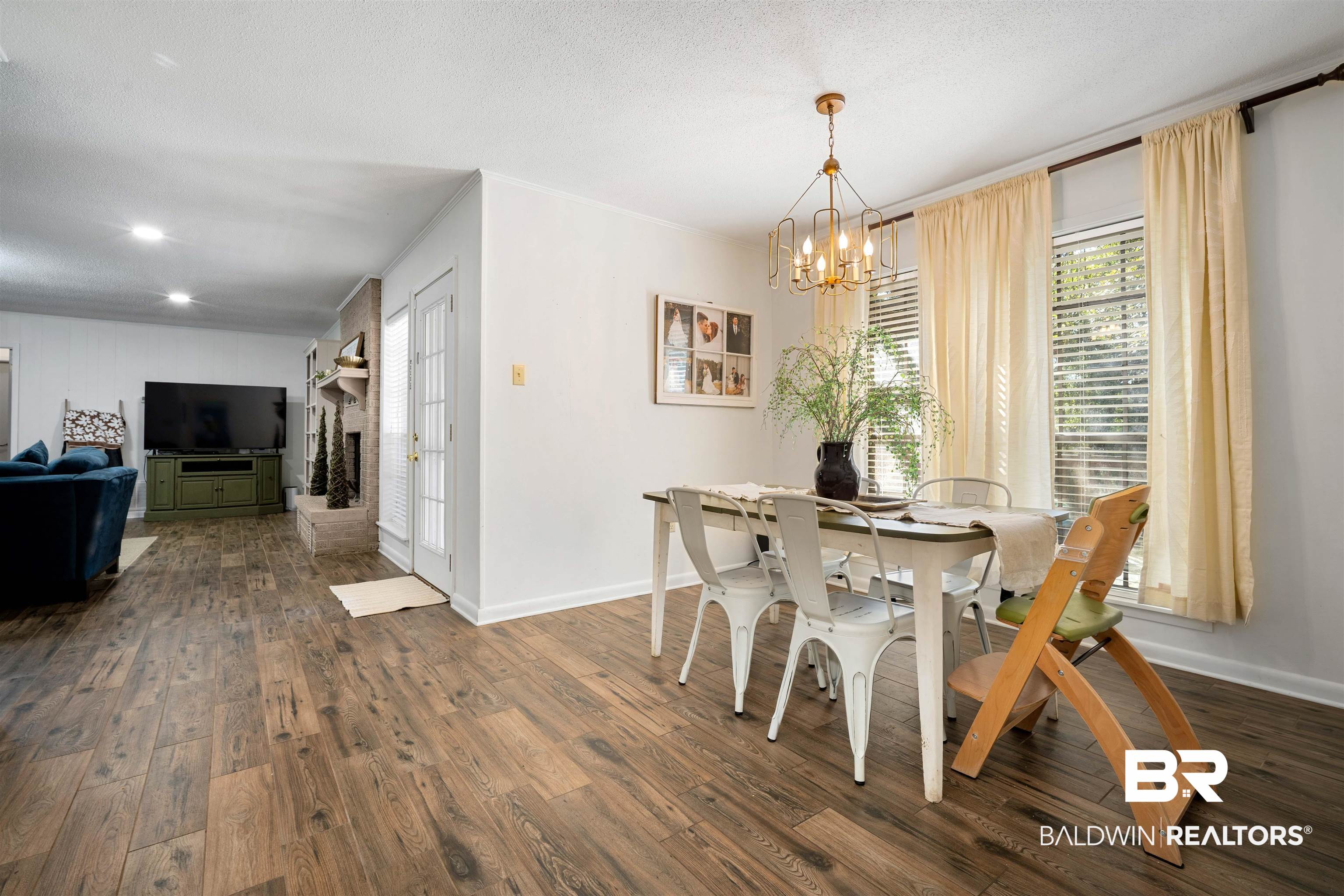 74 Caisson Trace Spanish Fort, AL 36527 - Photo 11 of 26 Dining room with dark wood-style floors, a chandelier, a brick fireplace, a textured ceiling, and ornamental molding