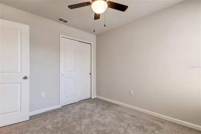 an empty room with closet and a chandelier fan