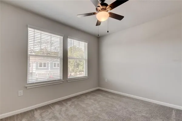 an empty room with a ceiling fan and carpet