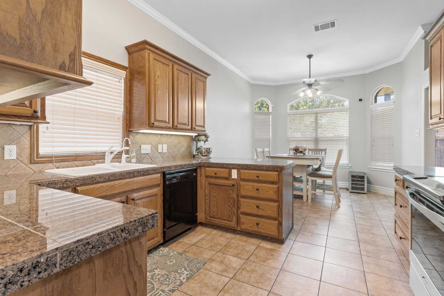 5614 100th Street Lubbock, TX 79424 - Photo 11 of 27 a large kitchen with kitchen island granite countertop a sink counter space and cabinets