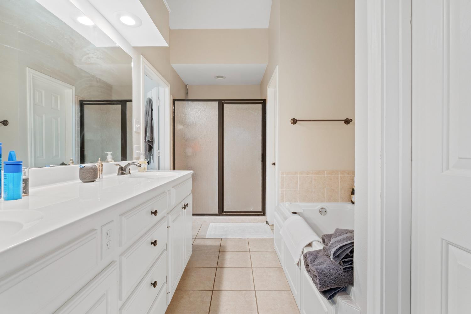 5614 100th Street Lubbock, TX 79424 - Photo 15 of 27 a bathroom with a double vanity sink and mirror with shower