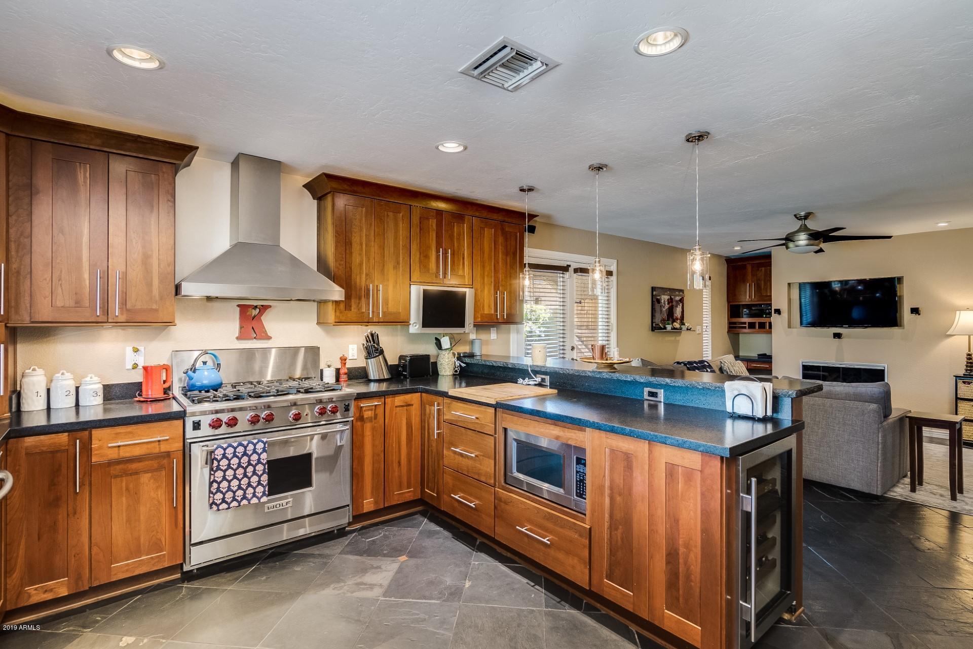5319 North 15th Street Phoenix, AZ 85014 - Photo 16 of 33 a kitchen with stainless steel appliances granite countertop a stove a sink dishwasher and a refrigerator with wooden floor
