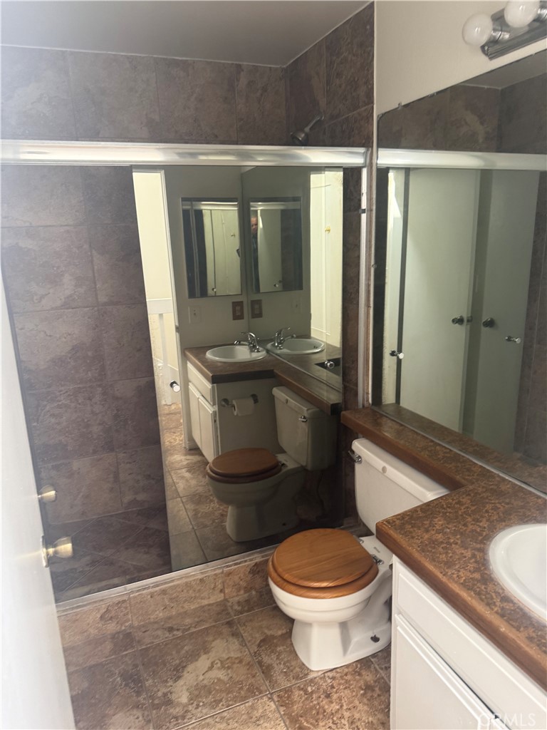 12750 Centralia Street, Unit 191 Lakewood, CA 90715 - Photo 24 of 38 a bathroom with a granite countertop sink a toilet a mirror and shower