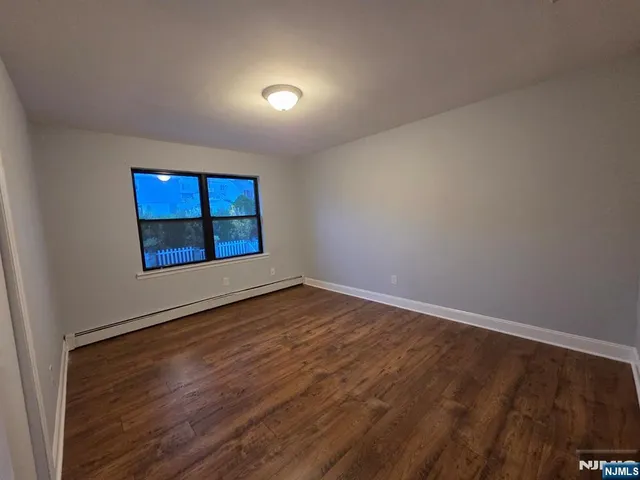 a view of an empty room with window and wooden floor