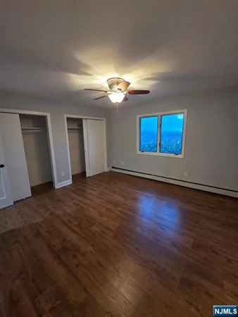 a view of an empty room with window and wooden floor