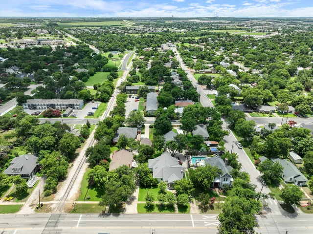 an aerial view of residential houses with outdoor space and trees