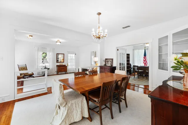 a dining room with wooden floor a chandelier a wooden table and chairs