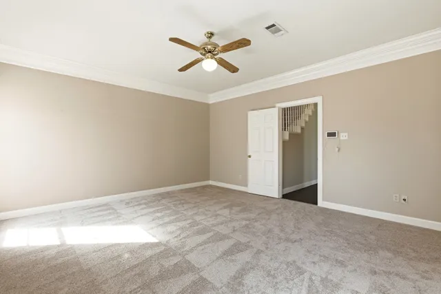 a view of an empty room with chandelier fan