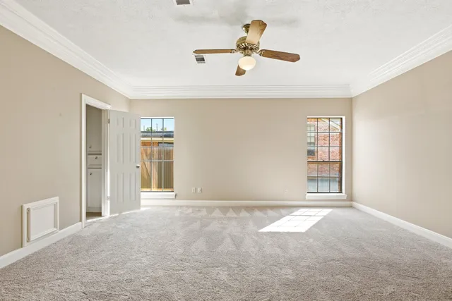 a view of an empty room with a window and kitchen view