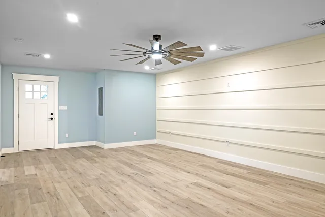 an empty room with wooden floor and windows