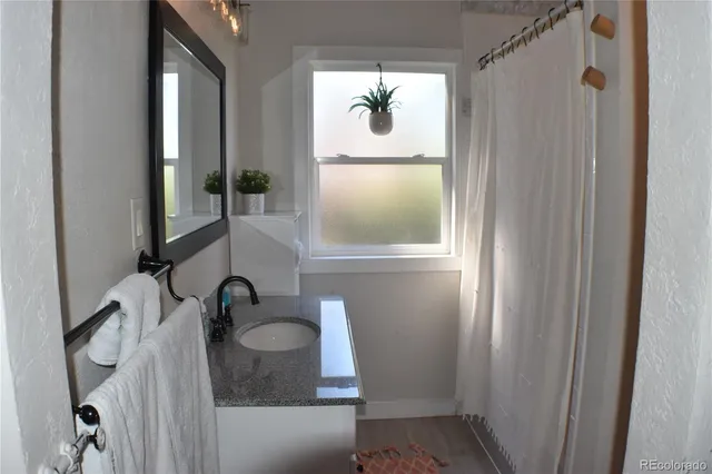 a bathroom with a granite countertop sink and a mirror