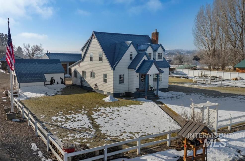 Snow covered property with a fenced front yard and a chimney
