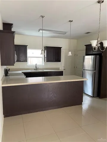 a kitchen with stainless steel appliances a refrigerator a sink a counter top space and cabinets