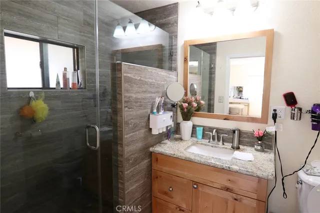 a bathroom with a granite countertop sink a mirror and a shower