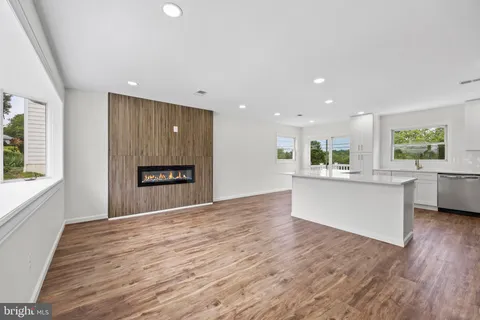a view of an empty room with a kitchen and window
