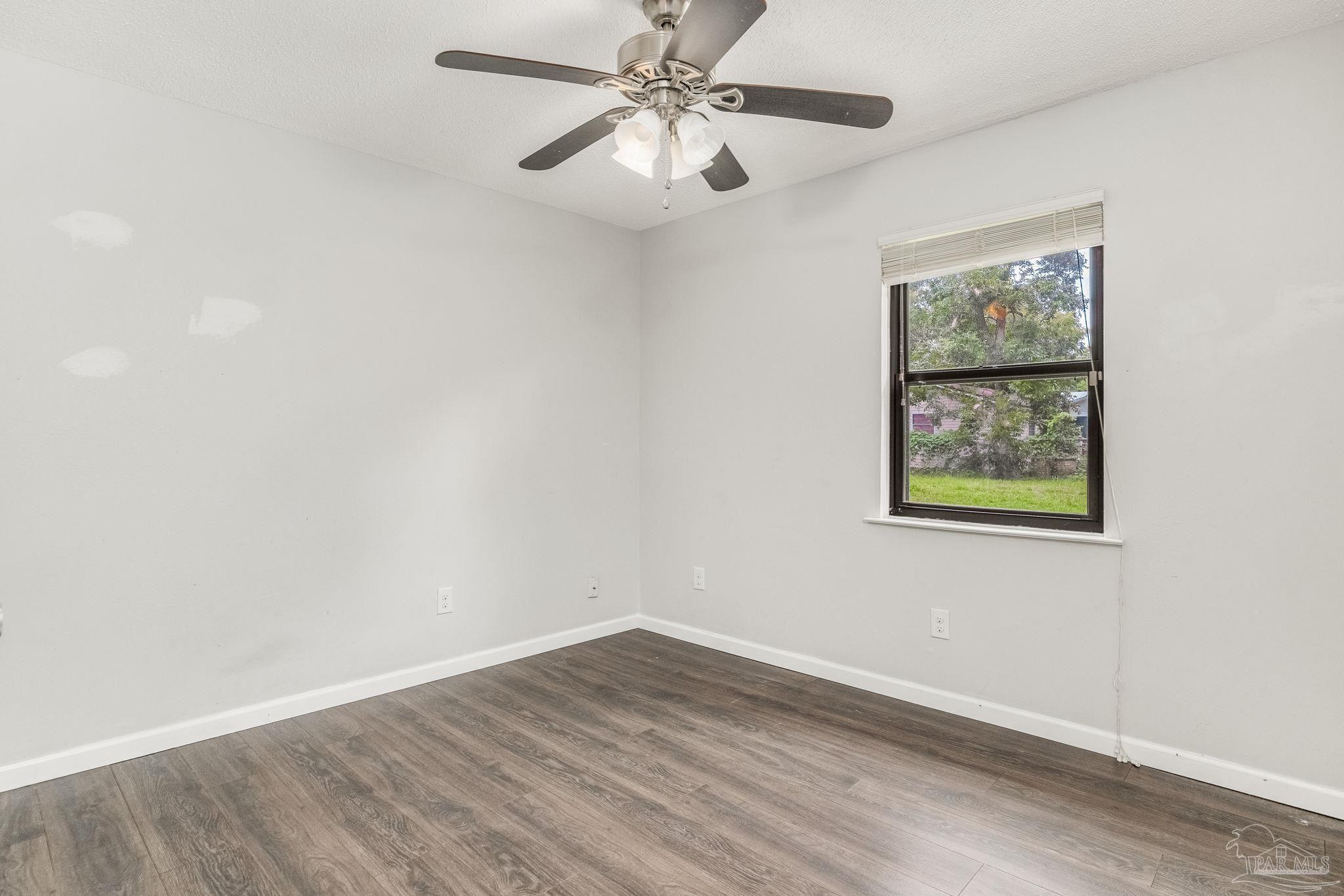 1422 Starlight Drive Cantonment, FL 32533 - Photo 19 of 49 an empty room with wooden floor chandelier fan and windows