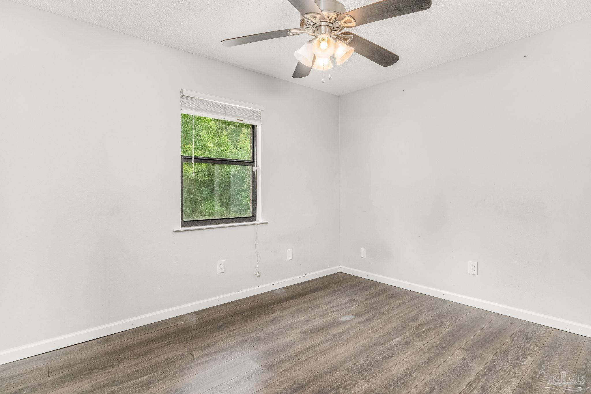 1422 Starlight Drive Cantonment, FL 32533 - Photo 22 of 49 an empty room with wooden floor fan and windows