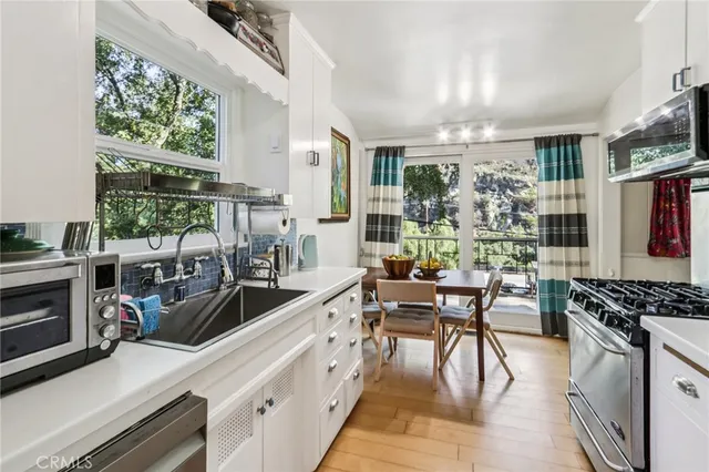 a kitchen with stainless steel appliances granite countertop a stove top oven a sink dishwasher a dining table and chairs with wooden floor