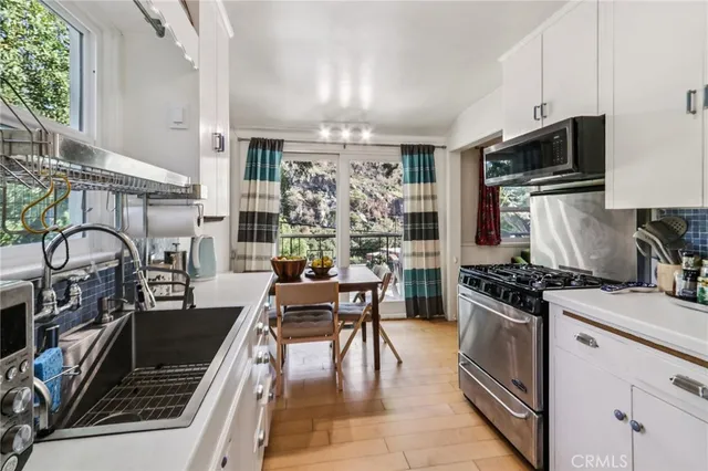 a kitchen with a stove a sink and a dining table with wooden floor