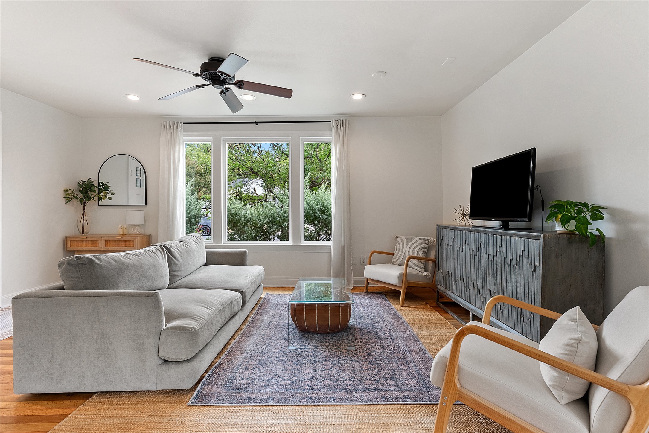 a living room with furniture a flat screen tv and a large window