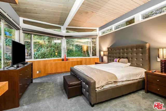 a bedroom with a large bed and a flat tv screen on dresser