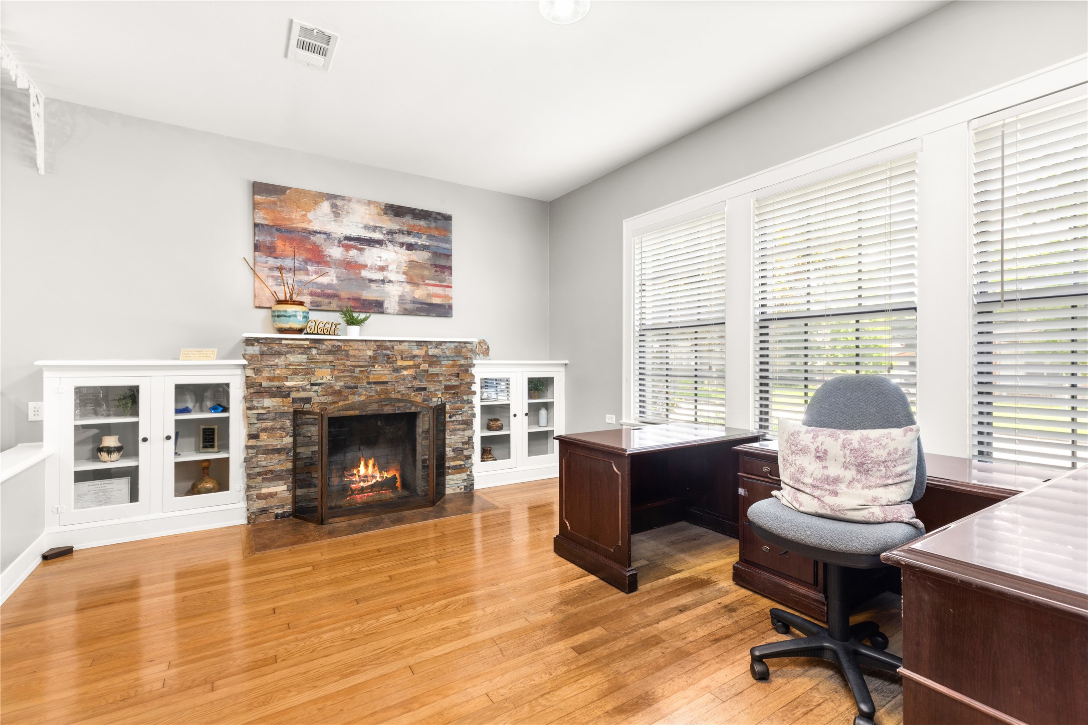 906 Higgins Street Humble, TX 77338 - Photo 18 of 26 Bright home with a cozy stone fireplace, built-in shelving, and large windows offering natural light. Ideal for productivity or relaxation.