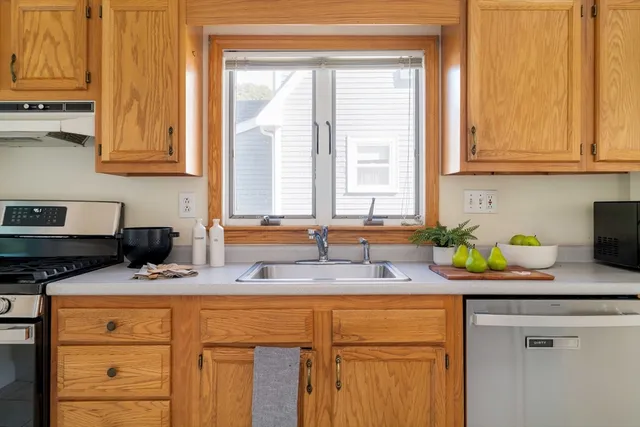 a kitchen with stainless steel appliances granite countertop a sink a stove and a window