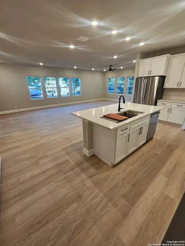 a large white kitchen with kitchen island a sink wooden floor and a fireplace