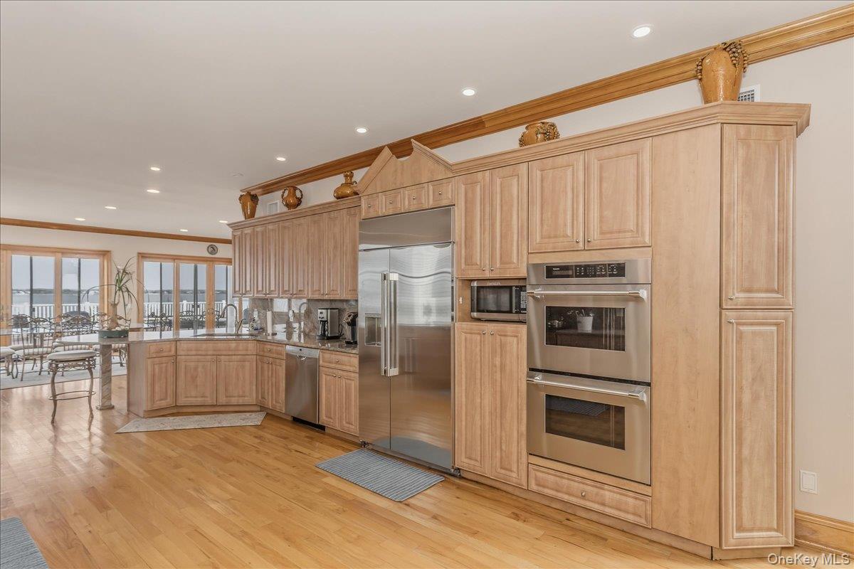 672 Dune Road Westhampton Beach, NY 11978 - Photo 14 of 38 a kitchen with stainless steel appliances wooden floor and chandelier